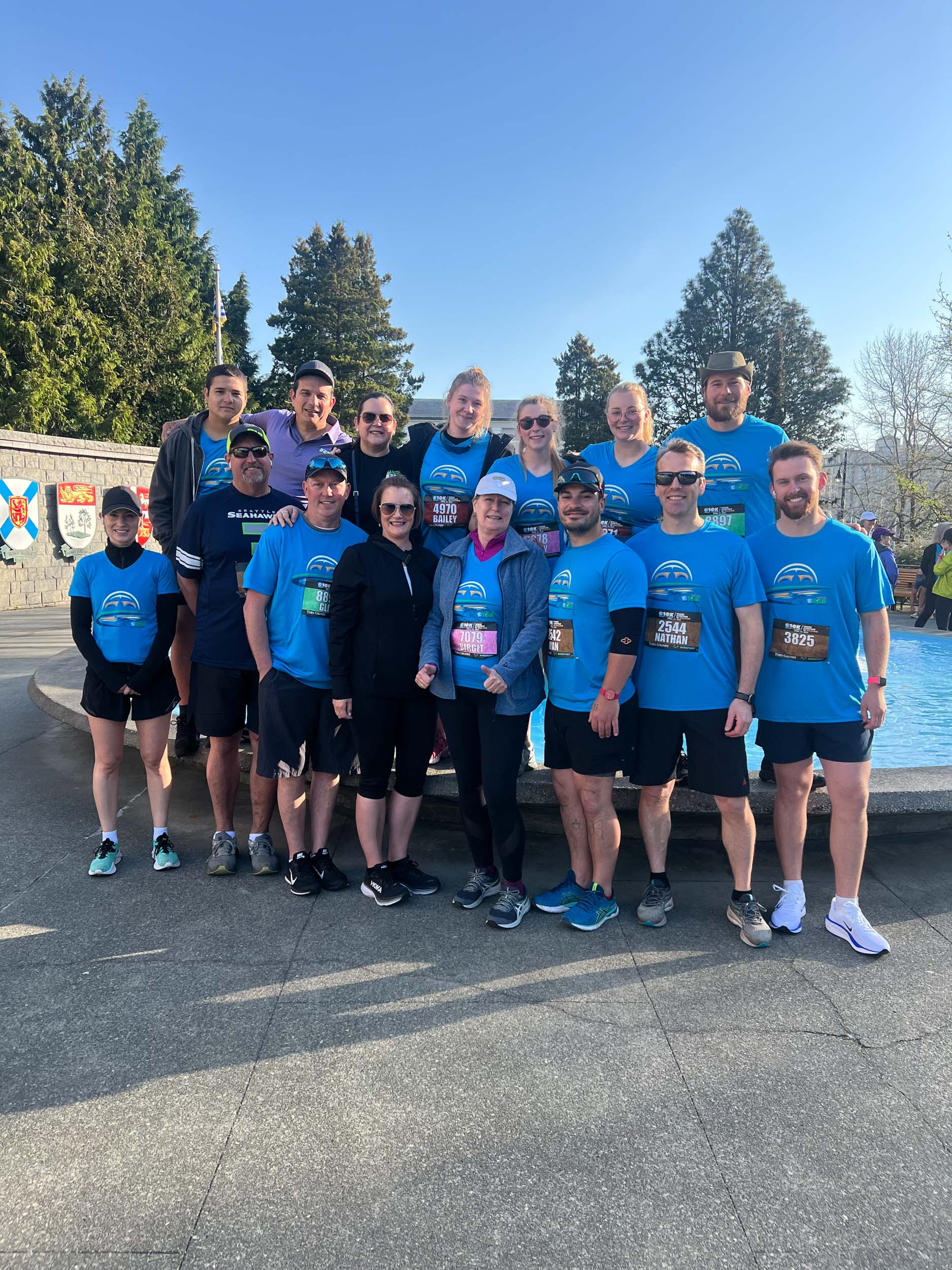 Team members in matching race jerseys posing for a photo in front of a water fountain